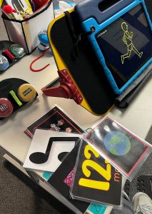 A variety of cards, signs and switches are on a table. In the center is a light box with a picture of a man running.