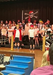 A large group of students are assembled on the stage. They are all dressed as pirates.