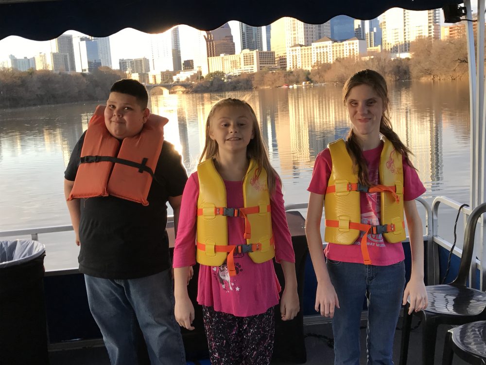 Students with life preservers stand on a boat