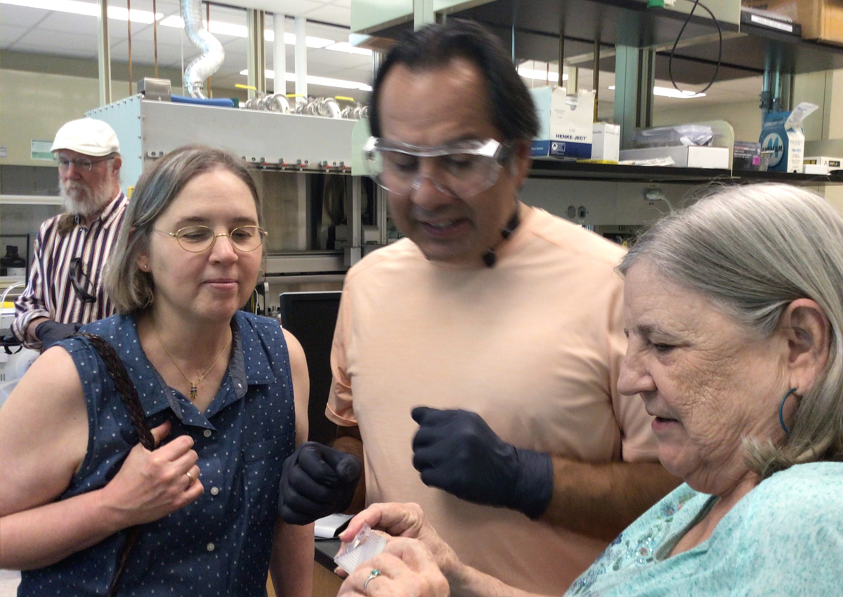 Four adults examine accessible chemistry tools in a chemistry lab at a university.