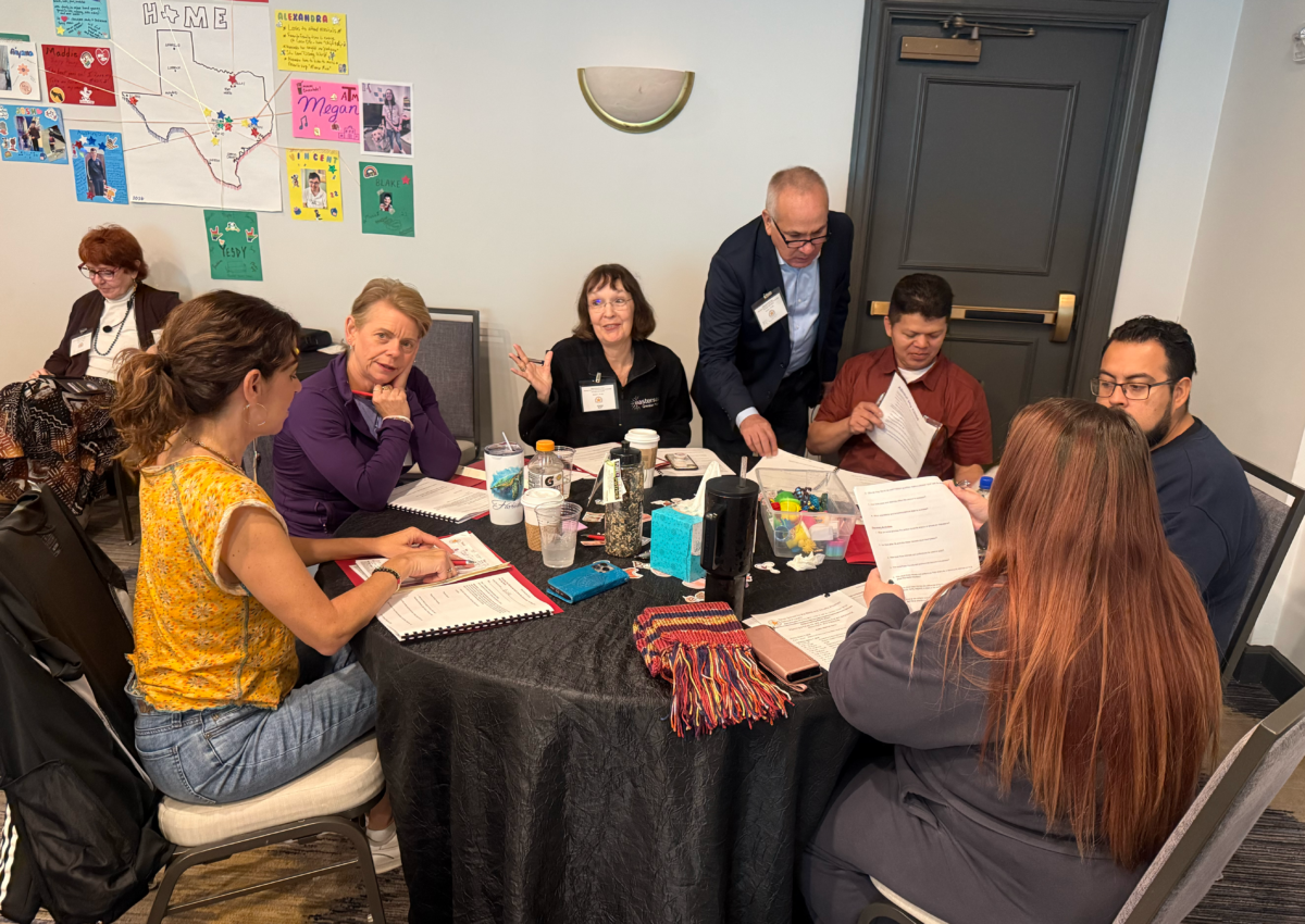 A group of adults sit around a table and talk among each other.