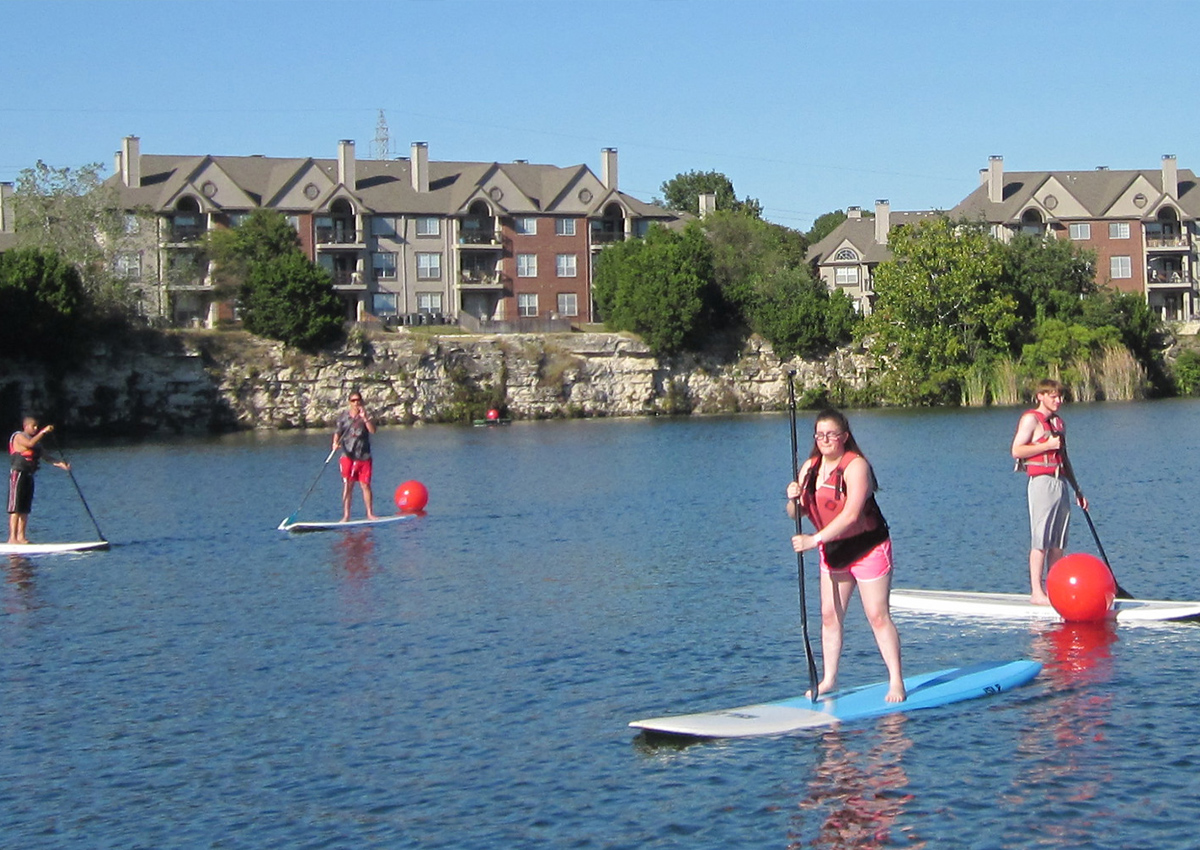 Students stand-up-paddle boarding.