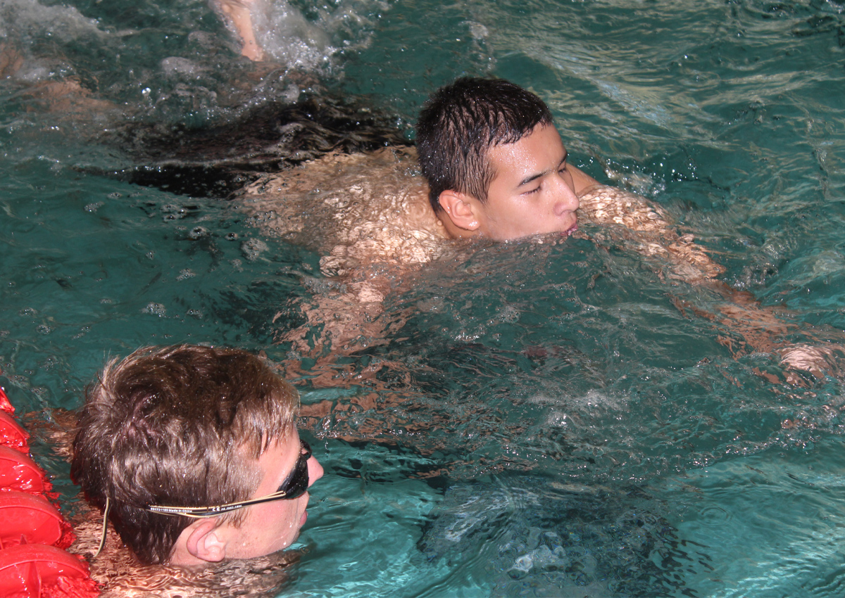 Student swimming in the pool with staff close by.