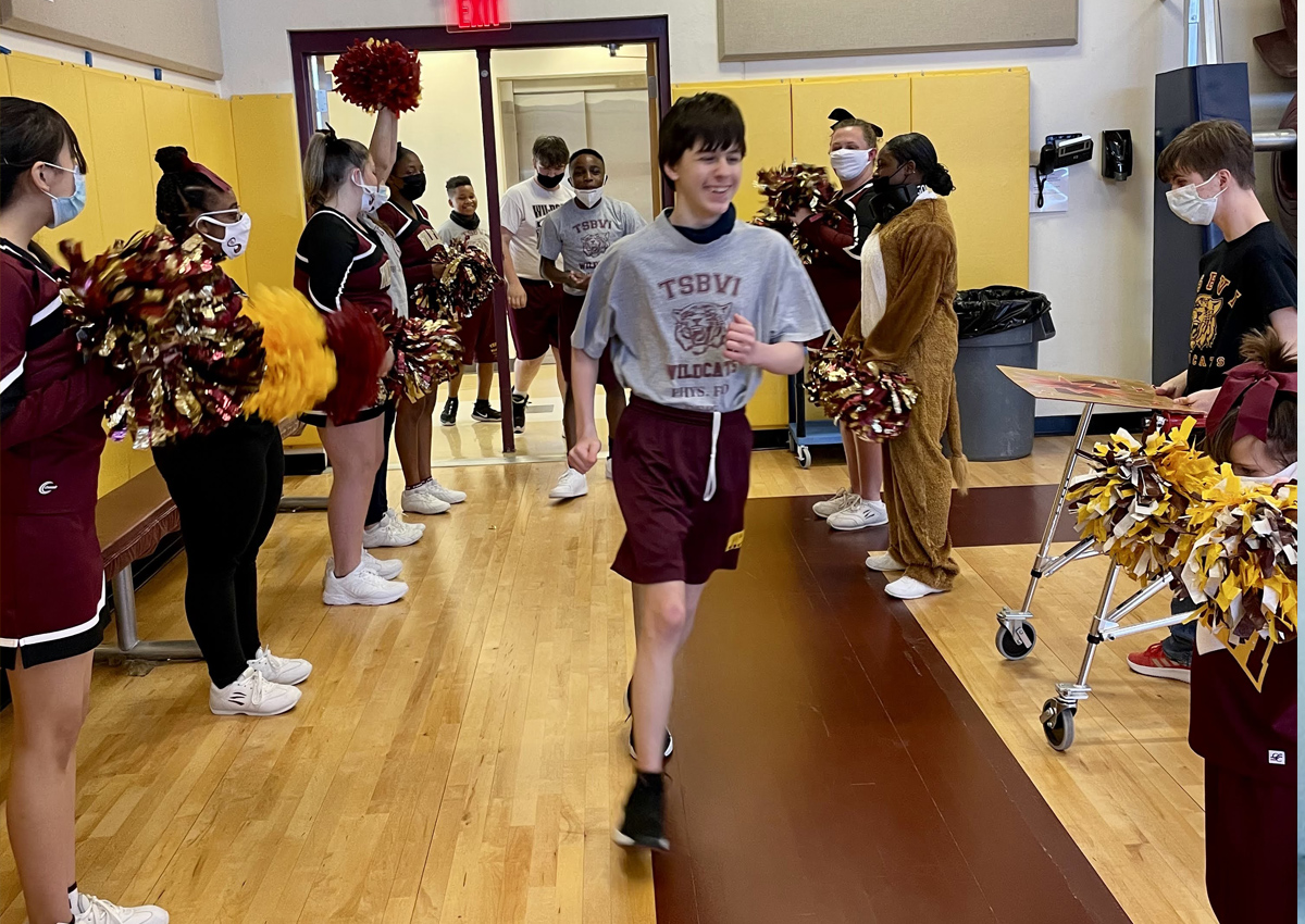 Cheerleaders and Mascot cheer on the sideline as Wrestlers enter the Pep Rally.