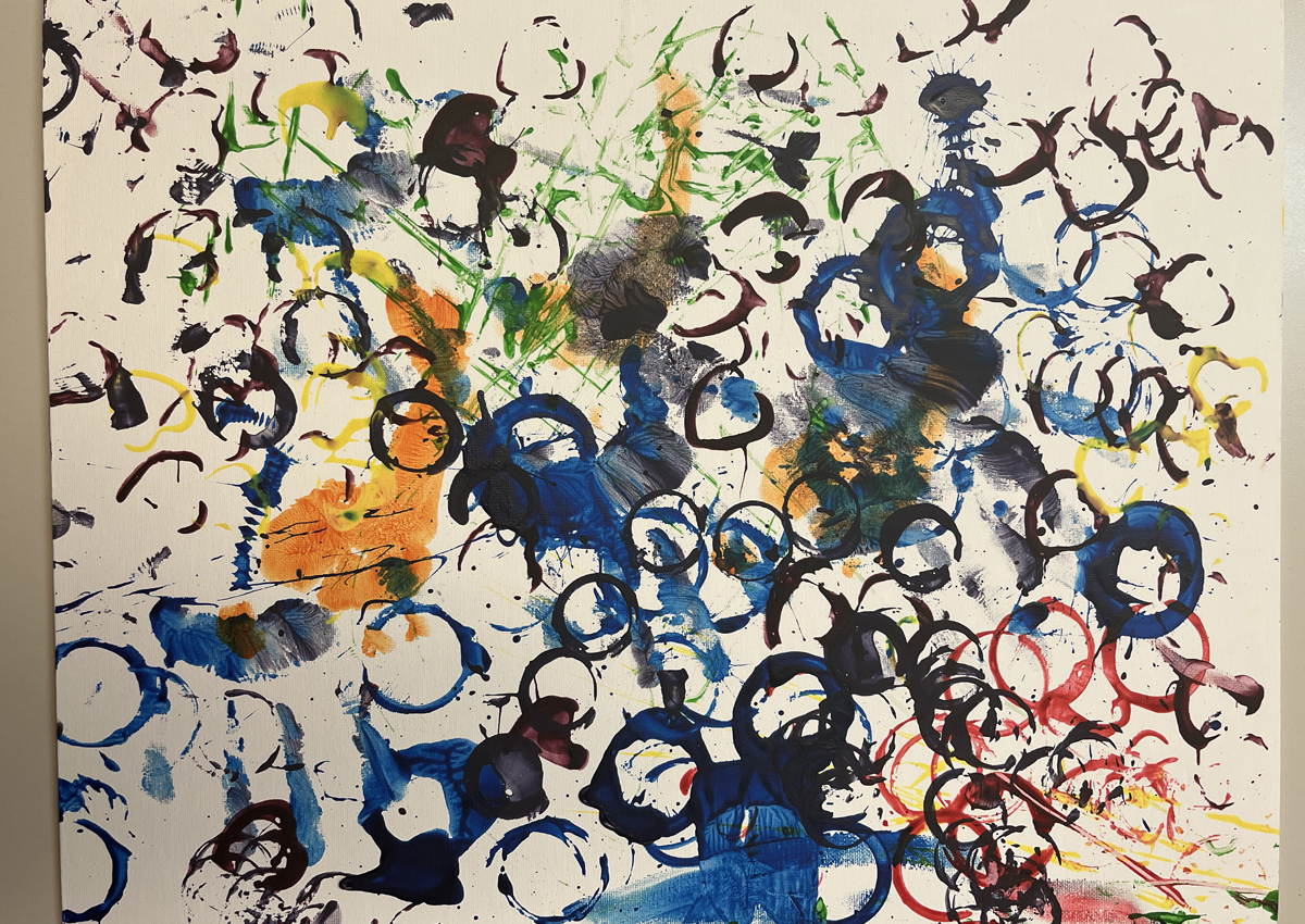 Numerous and colorful paint marks made by hands, feet, heart shaped slinky, race car wheels, circles, and splats.