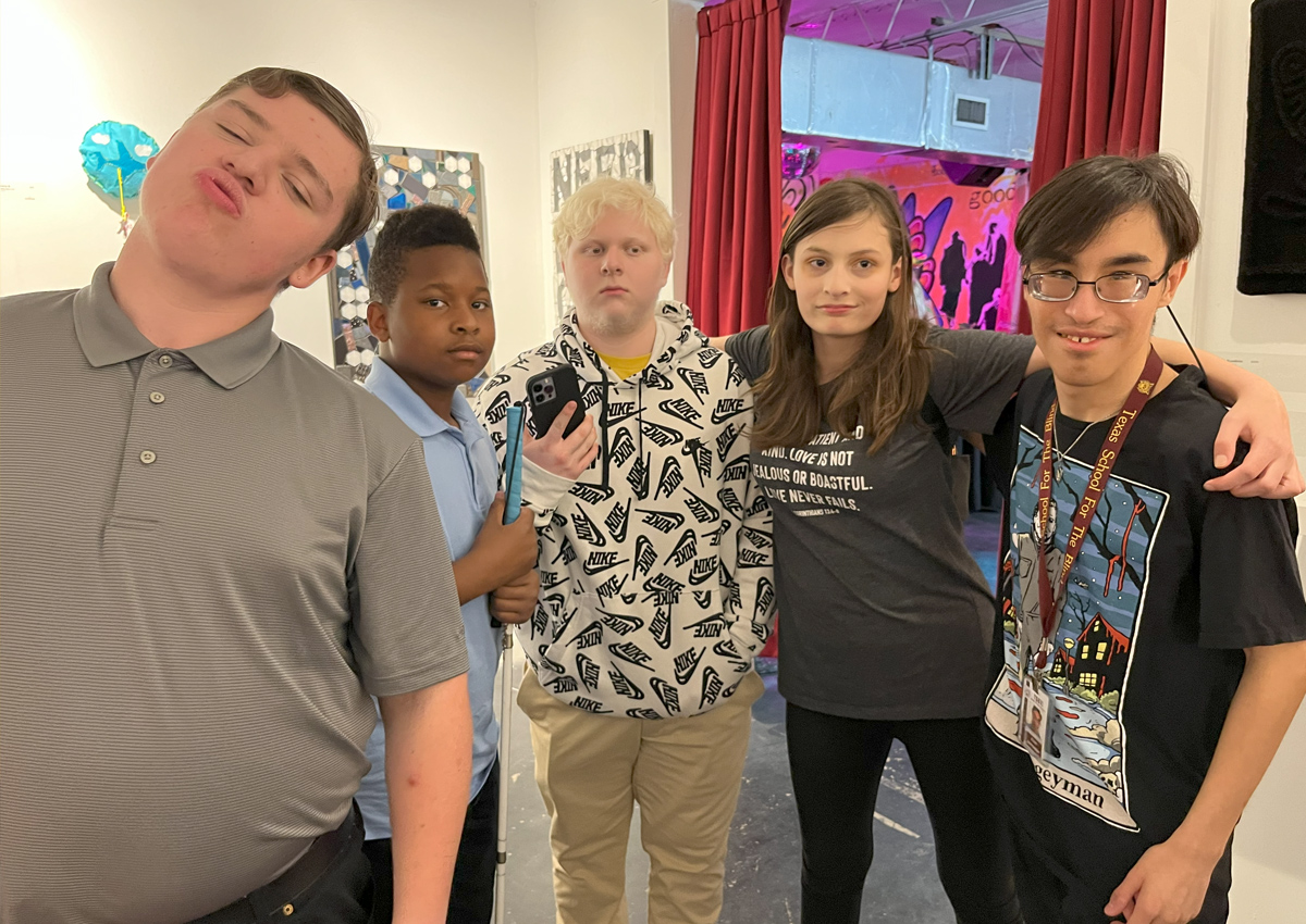 Five adolescents pose together in an art gallery.