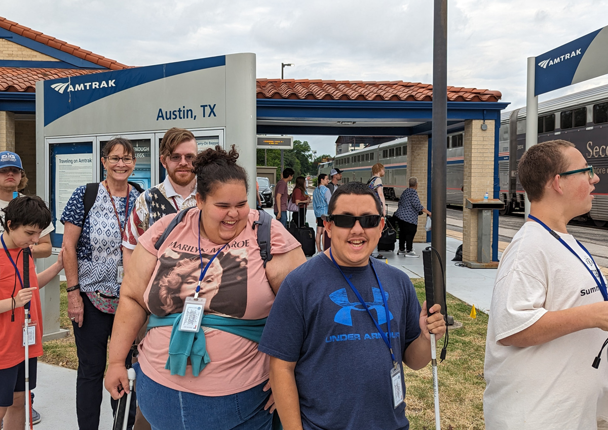 Two adults and four adolescents wait on the Amtrak platform at the downtown Austin station.