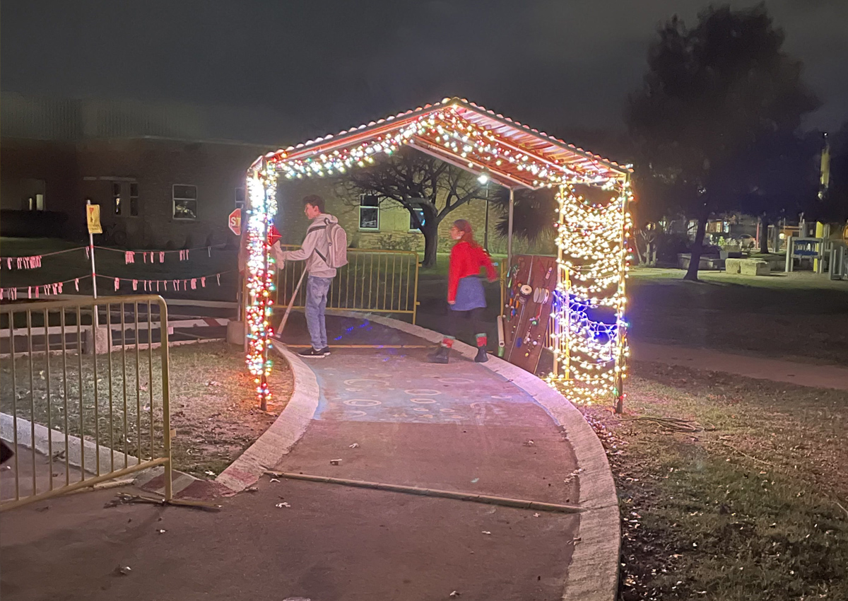 A carport on a track decorated in hundreds of Christmas lights
