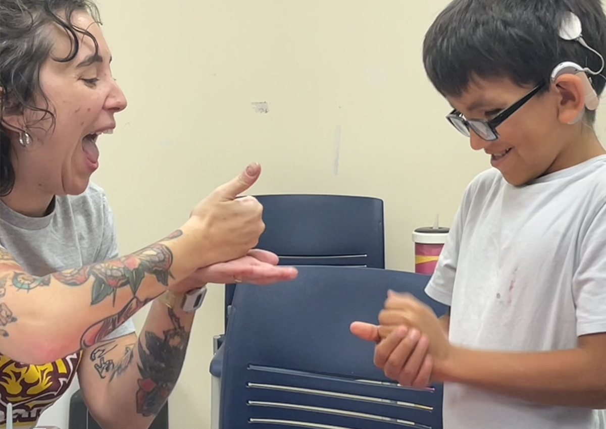An adult and elementary student both sign 