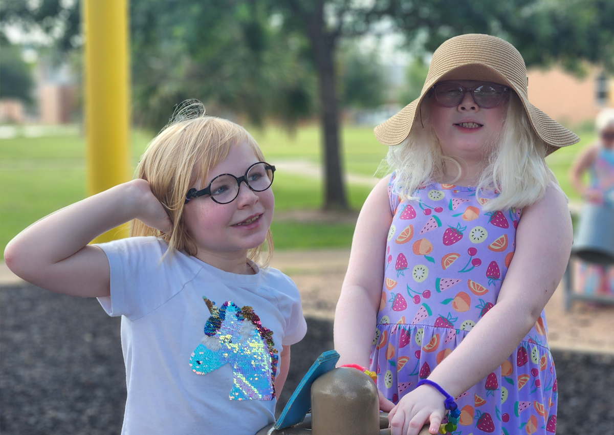 Two adolescents stand in a playground.