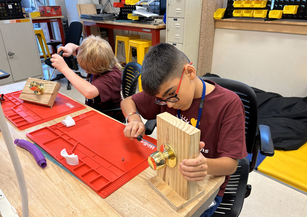 Two adolescents work on door knob assembly in a MakerSpace.