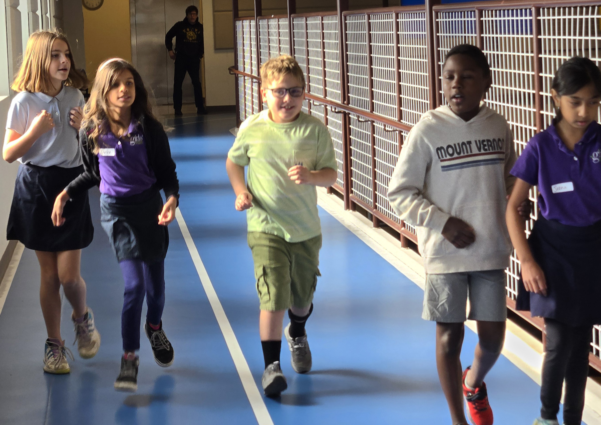 Five adolescents walk/run an indoor track.