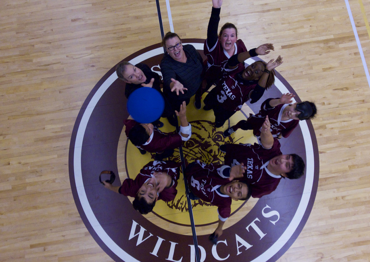 Texas team standing on the Wildcats logo in center court throwing the goalball into the air.
