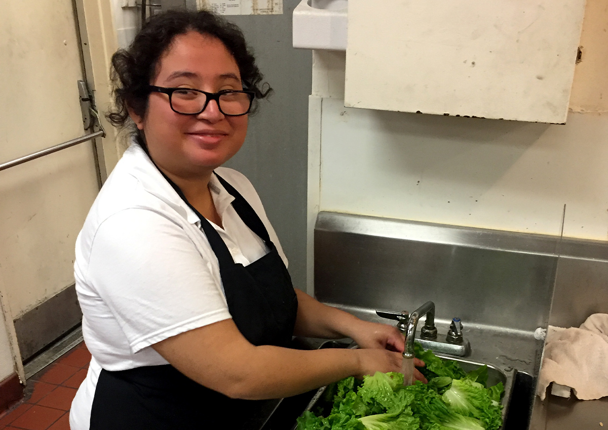 Student volunteer washing vegetables in a hotel kitchen
