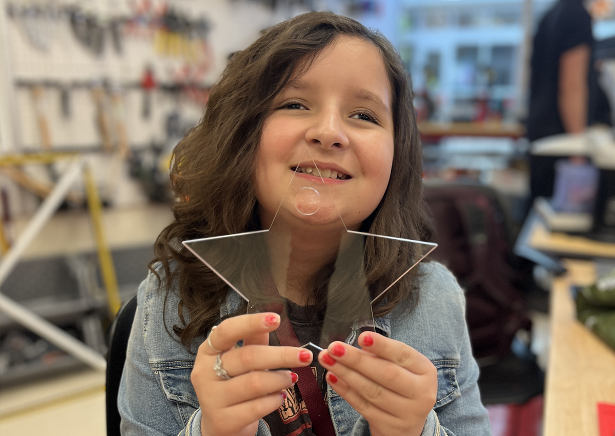 An adolescent holds up a 6 inch shiny and translucent star keychain.