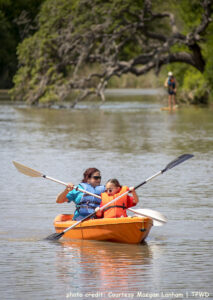 An adult and adolescent wearing sunglasses kayak on the water. Photo credit: Courtesy Maegan Lanham, TPWD