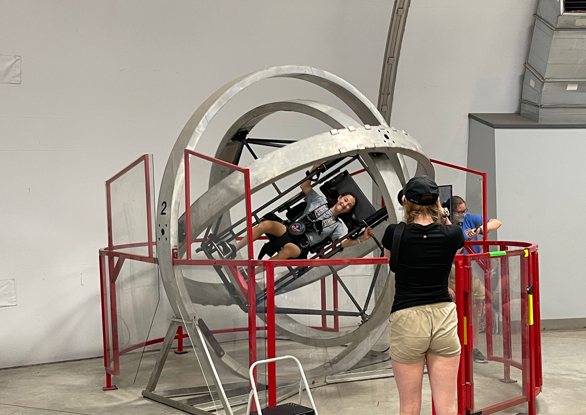 An adolescent strapped into an aerotrim, a 3-axis gimbal large enough to contain a human being.