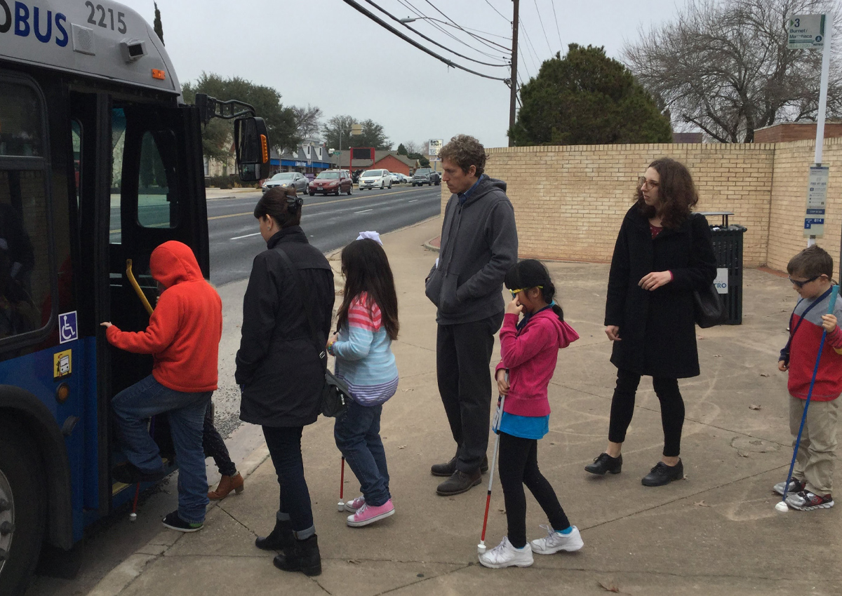 Young students boarding CapMetro bus with TVIs.