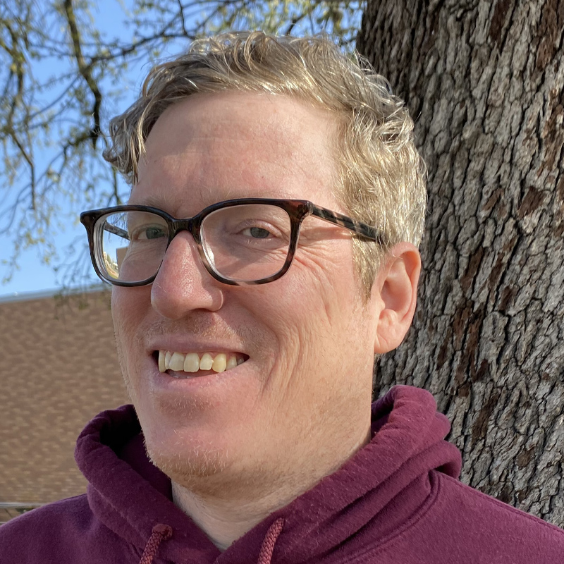 John smiling beneath a tree