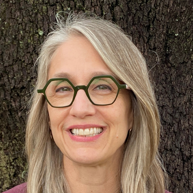 Sara smiling under a tree.