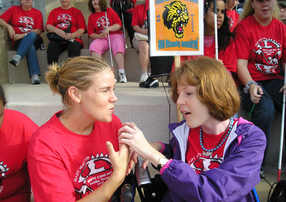 An adult and adolescent use tactile sign language at City Hall during White Cane Day 2005.