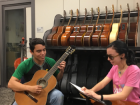 Image of a young man playing the guitar next to a girl singing while reading braille lyrics