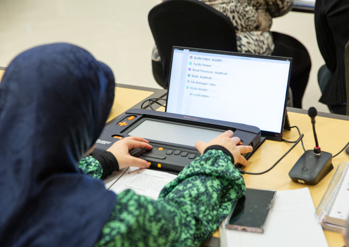 An adult uses the Monarch braille display attached to a monitor.