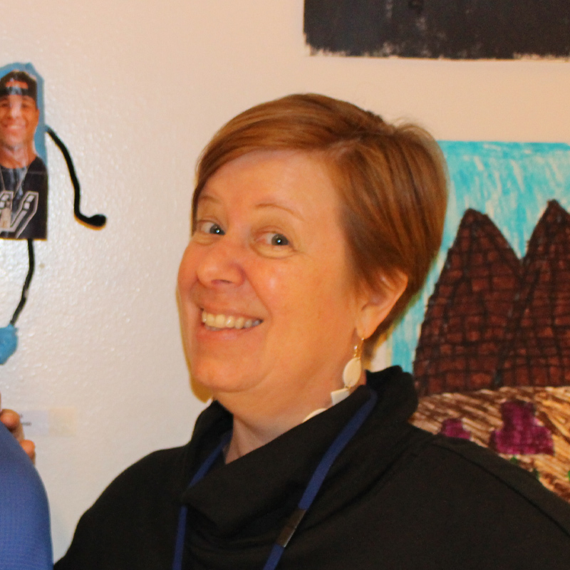 Gretchen Bettes standing in front of a wall with three pieces of art