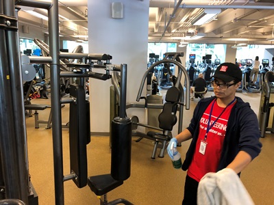 Student cleaning gym equipment