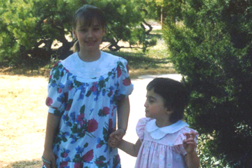two girls wearing flowered dresses and holding hands