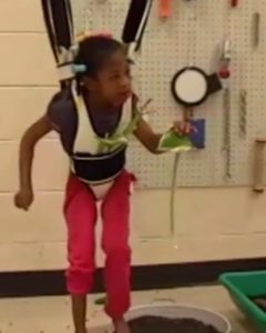 A young girl in a hopsa dress explores a plant