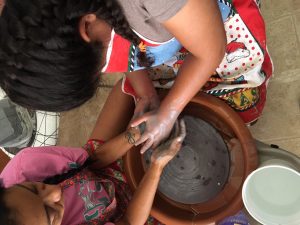 Tanya and her intervener work with clay on a ceramics wheel.