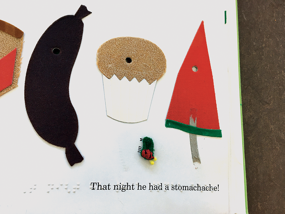 Picture of a book with tactile images of a sausage, muffin, watermelon, and the caterpillar. “That night he had a stomach ache” is written in Braille and print.