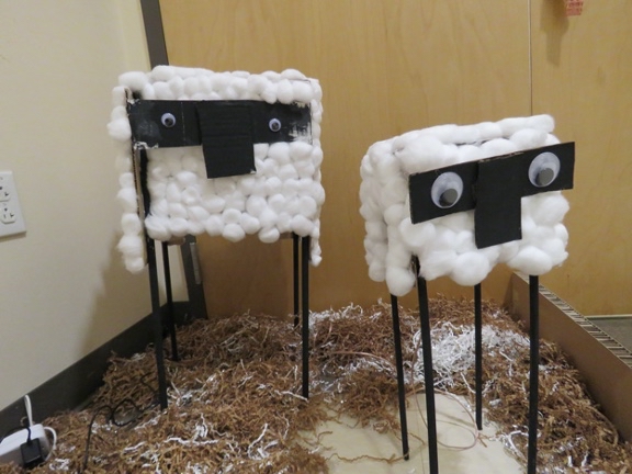 Two cardboard sheep made with cotton balls and googly eyes