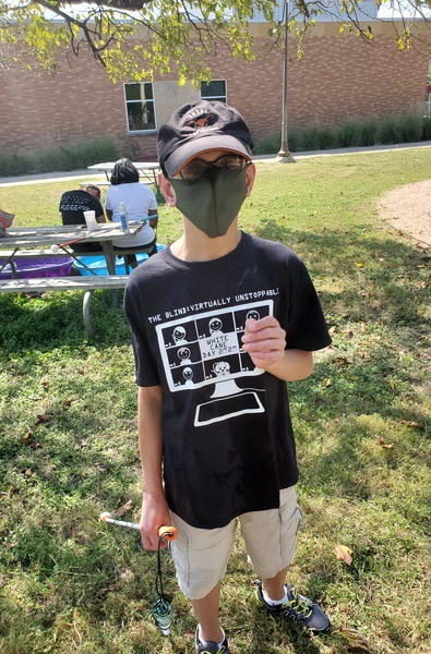 A student wears a green mask while outside on the TSBVI campus.