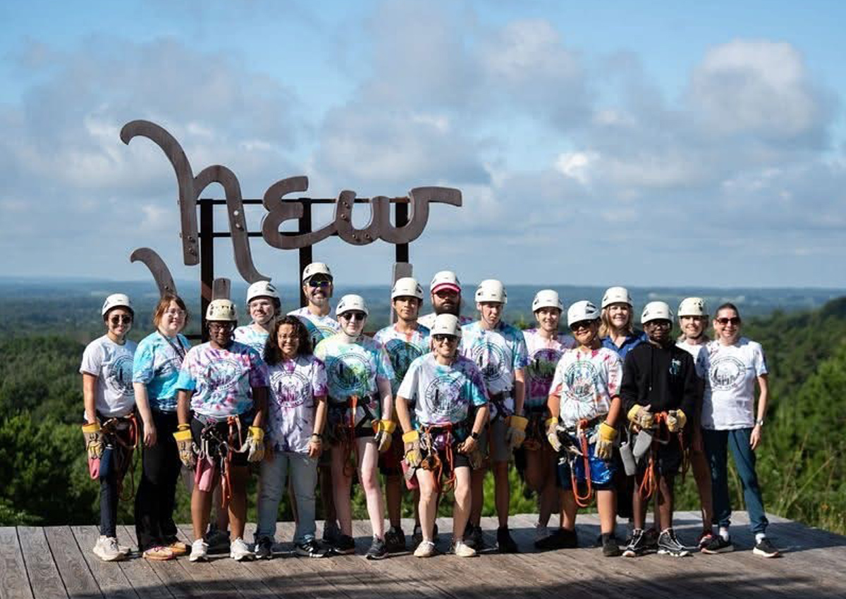 Estudiantes y personal equipados con cascos y arneses de tirolesa observan el bosque del este de Texas.