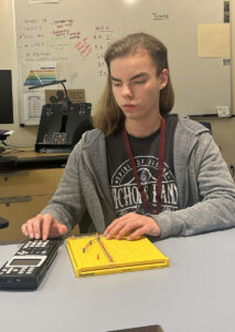A student uses a talking graphing calculator and a graph board to complete an algebra problem.