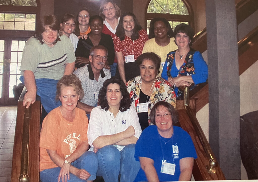 Thirteen smiling leaders gather on the stairs.