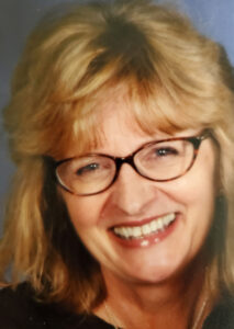 A smiling woman with blonde hair and glasses.