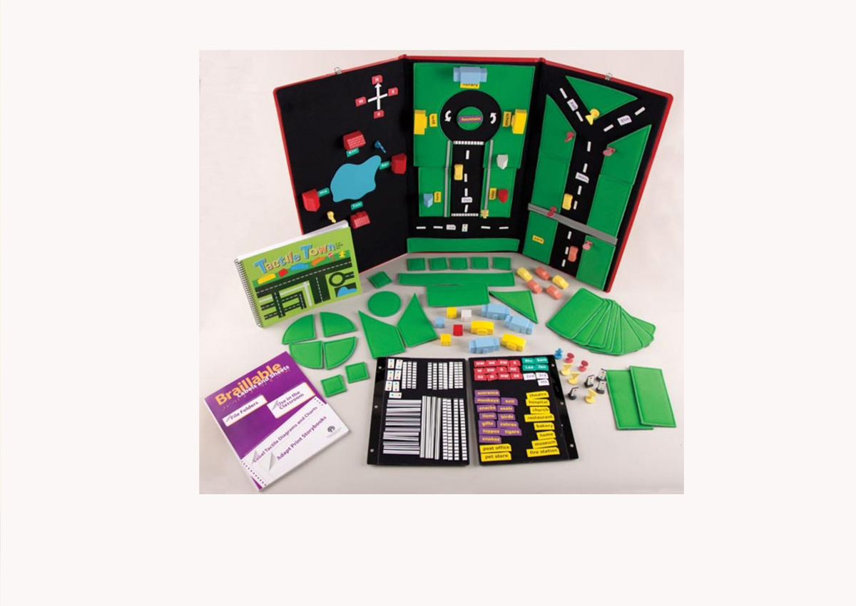 A black velcro board with pieces that represent grass, street crossings, and different kinds of brightly colored buildings that attach to it.