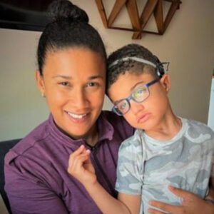 A woman and a young man smiling together on a couch.
