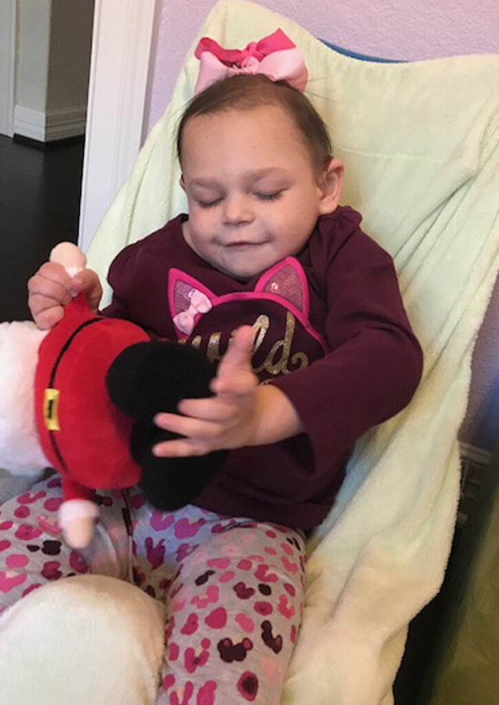 Abbey explora un Santa Claus de peluche usando sus manos mientras está sentada en una silla ergonómica.