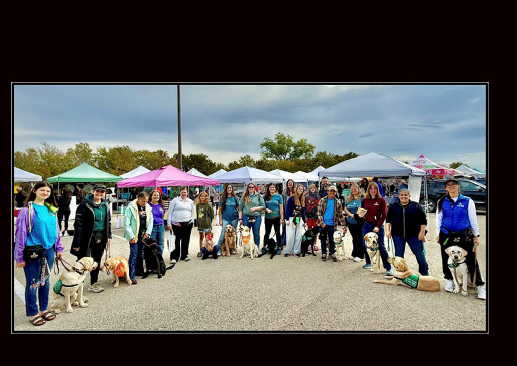 Criadores de cachorros de Austin GDB posan en semicírculo con sus perros durante una salida en grupo a un mercado de agricultores local.