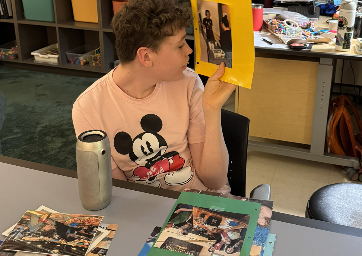 An adolescent sits at a table and looks at a bright yellow piece of paper with the word 