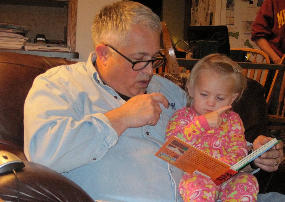 A man reads a book to a young girl.